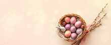Basket With Painted Easter Eggs, Bunny And Willow Branches On Light Background With Space For Text