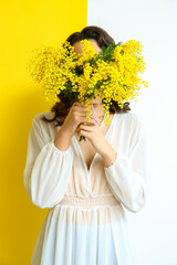 Canvas Print - Beautiful young woman with mimosa flowers on yellow and white background