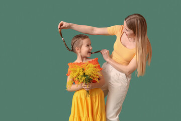 Canvas Print - Little girl with mimosa flowers and mother on green background