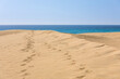 Fußspuren auf einer Düne im Sand vor dem Meer des Atlanik in den Dünen von Maspalomas auf Gran Canaria