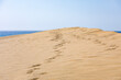 Fußspuren auf einer Düne im Sand vor dem Meer des Atlanik in den Dünen von Maspalomas auf Gran Canaria