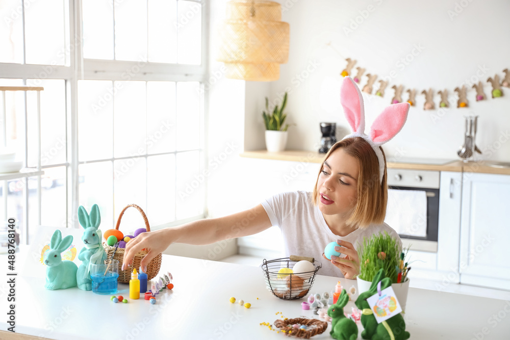 Beautiful woman painting Easter eggs at home