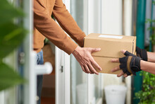 Close-up Of Delivery Man Delivering The Parcel To The Client To Home