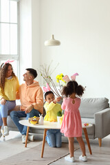 Wall Mural - Little children with their parents decorating tree branches at home on Easter day