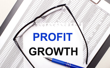 Fototapete - On a light background, a report, black-framed glasses, a pen and a sheet of paper with the text PROFIT GROWTH Business concept