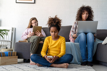 Wall Mural - Happy multiethnic teenagers holding technology gadgets using digital devices studying together.