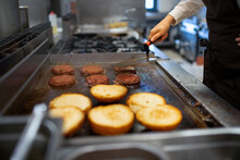 Close-up Of Professional Female Chef Preparing Burgers Indoors In Restaurant Kitchen.