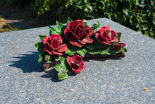 Mourning Background. Red Ceramic Rose Flowers On Tomb In Cemetery. France. Traditional Ceramic Grave Decoration. Loss, Grief, Sorrow, Memorial, Funeral Services Business Concepts. Selective Focus