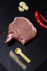 Canvas Print - A piece of pork meat on a black background. Raw meat on a dark dish. Fresh and tender piece of meat.