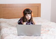 © gmstockstudio - Little girl using the laptop with earphones