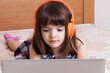 © gmstockstudio - Little girl using the laptop with earphones