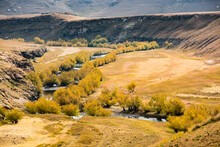 Travel To Lesotho. A Tree-lined River Flows Through A Meadow