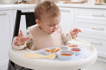 Sticker - Cute little baby eating food in high chair at kitchen