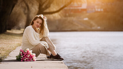 Beautiful girl with tulip flowers in her hands walks in the park 