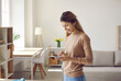 © Studio Romantic - Woman using mobile phone. Happy beautiful young lady standing in living room, holding new cellphone, communicating with friend on social media, texting on messenger app, reading replies and smiling