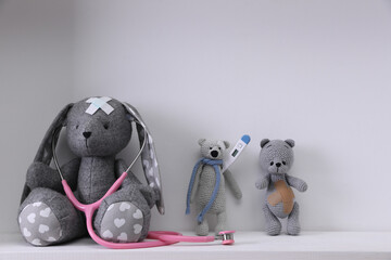 Canvas Print - Toys with stethoscope, thermometer and sticking plasters on white table against light grey background. Children's hospital