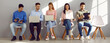 © Studio Romantic - Young people holding paper documents, resumes and laptops are sitting in line for interview. Men and women in casual clothes communicate and prepare for business meeting at staffing agency. Banner.
