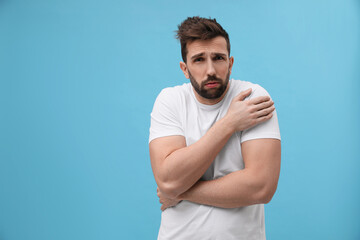 Wall Mural - Man suffering from fever on light blue background, space for text. Cold symptoms