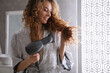 © New Africa - Beautiful woman using hair dryer in bathroom