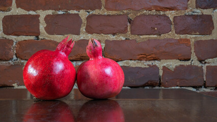 Whole two red pomegranate on red brick wall background. Garnet is a symbol of Judaism, top view.