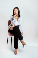 Full length portrait of smiling attractive businesswoman in suit posing while standing with arms crossed and looking at camera isolated over white background