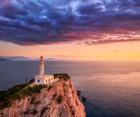 Wall Mural - lighthouse on the mountain peak at colorful sunset in summer. aerial view. beautiful lighthouse on t