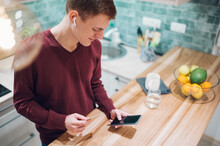 Redhead Man Using Smartphone And Credit Card In The Kitchen At Home