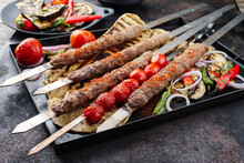 Traditional Turk Adana Kebap On Shashlik Skewer With Barbecue Vegetable And Flatbread Served As Close-up On A Rustic Metal Tray