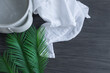 clay basin of water, white linen and green palm branch on a dark wood background with copy space