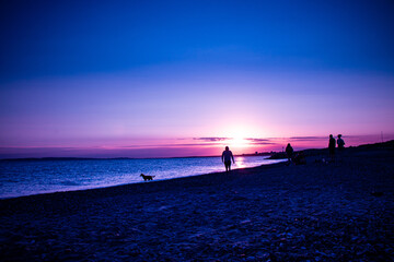 Wall Mural - The Beautiful shot purple beach scene and people silhouettes at sunset