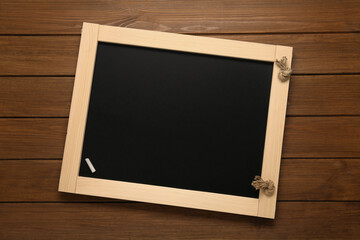 Canvas Print - Clean blackboard with piece of white chalk on wooden table, top view