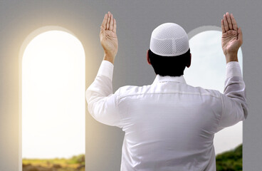 Wall Mural - Rear view of Asian Muslim man standing while raised hands and praying