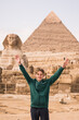 man against the background of the Egyptian pyramids. Hands up.