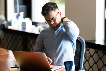 Tired businessman using laptop in his office. Angry man working on the project.