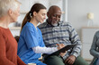 © Prostock-studio - Supportive nursing home attendant helping senior black man filling papers
