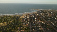 Aerial Wide Shot Showing Punta Del Diablo City With Sandy Beach And Atlantic Ocean During Sunset Time In Uruguay - Punta Del Diablo Is A Village And Seaside Locality In Uruguay, Rocha Department.