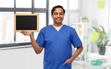 Sticker - healthcare, profession and medicine concept - happy smiling male doctor or nurse in blue uniform with chalkboard over medical office at hospital background