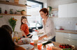© Halfpoint - Mother of three little children preparing breakfast in kitchen at home.