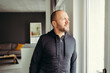 © contrastwerkstatt - Thoughtful bearded man looking out through window at home