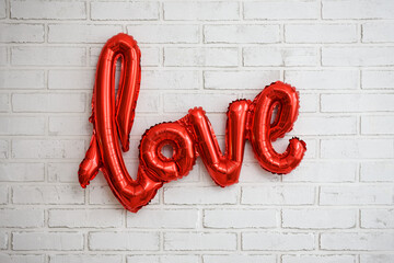 Wall Mural - red foil air balloon love letters over white brick wall background