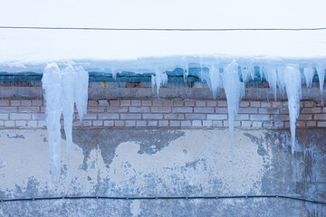  Bright, vivid and colorful background of icicles hanging from the rim of the roof. The spring or winter background of melting ice and snow in the sunny day