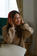 © saltdium - A portrait of young pretty Asian woman in casual outfit sitting on a floor relaxing with headphones on , for home and music concept.