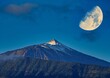 Blick auf den verschneiten Gipfel des höchsten Berges Spaniens den Teide mit Vollmond am Himmel