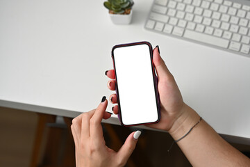 Poster - Top view of hands holding a smart phone with a blank white screen leaning on an office table with keyboard, for business and technology concept.