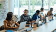 © Tijana - Group of Business People Sitting in a Row and Working in Open Plan Office. Five colleagues talking and typing business report on a laptop computers while sitting at same desk in a modern office.