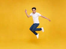 Happy Asian Man Smiling And Jumping While Celebrating Success Isolated Over Yellow Background.