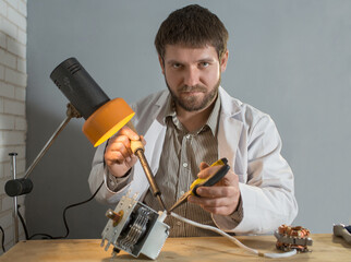 Wall Mural - a man soldering iron solders a part from an electrical appliance. the concept of repair of equipment