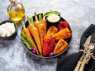 Poster - baked roast baby carrots, bell pepper in a plate, basil and spices vegan dish close up, white sauce, close up