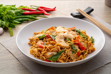 Wall Mural - Spicy stir fried instant noodle with sliced chicken breast and thai basil leaves in white plate