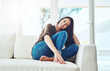 © Nikish H/peopleimages.com - This is a place I like to call home. Portrait of a happy young woman sitting on her sofa at home.